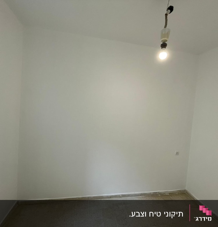 קיר לבן צבוע עם נורה תלויה מהתקרה